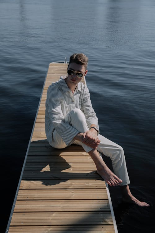 Man Sitting and Posing on Wooden Pier