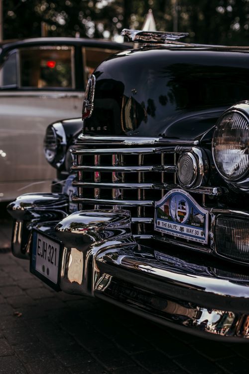 Free Detailed close-up of a vintage black car with chrome accents, showcasing its classic front grille and elegant design. Stock Photo