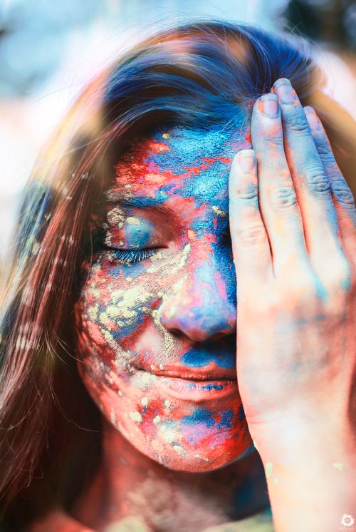 Free Vibrant portrait of a woman with colorful powdered paint on her face, eyes closed. Stock Photo
