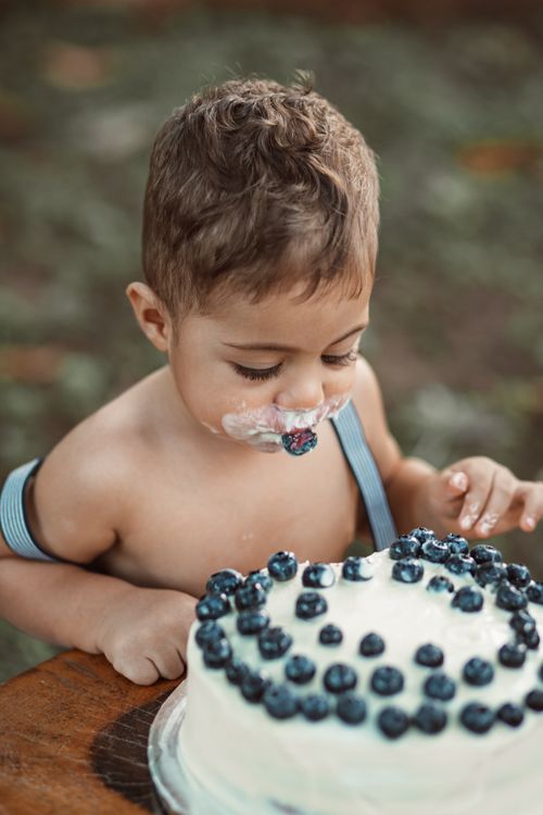 Free A cute child enjoying a homemade blueberry cake outdoors on a sunny day. Stock Photo