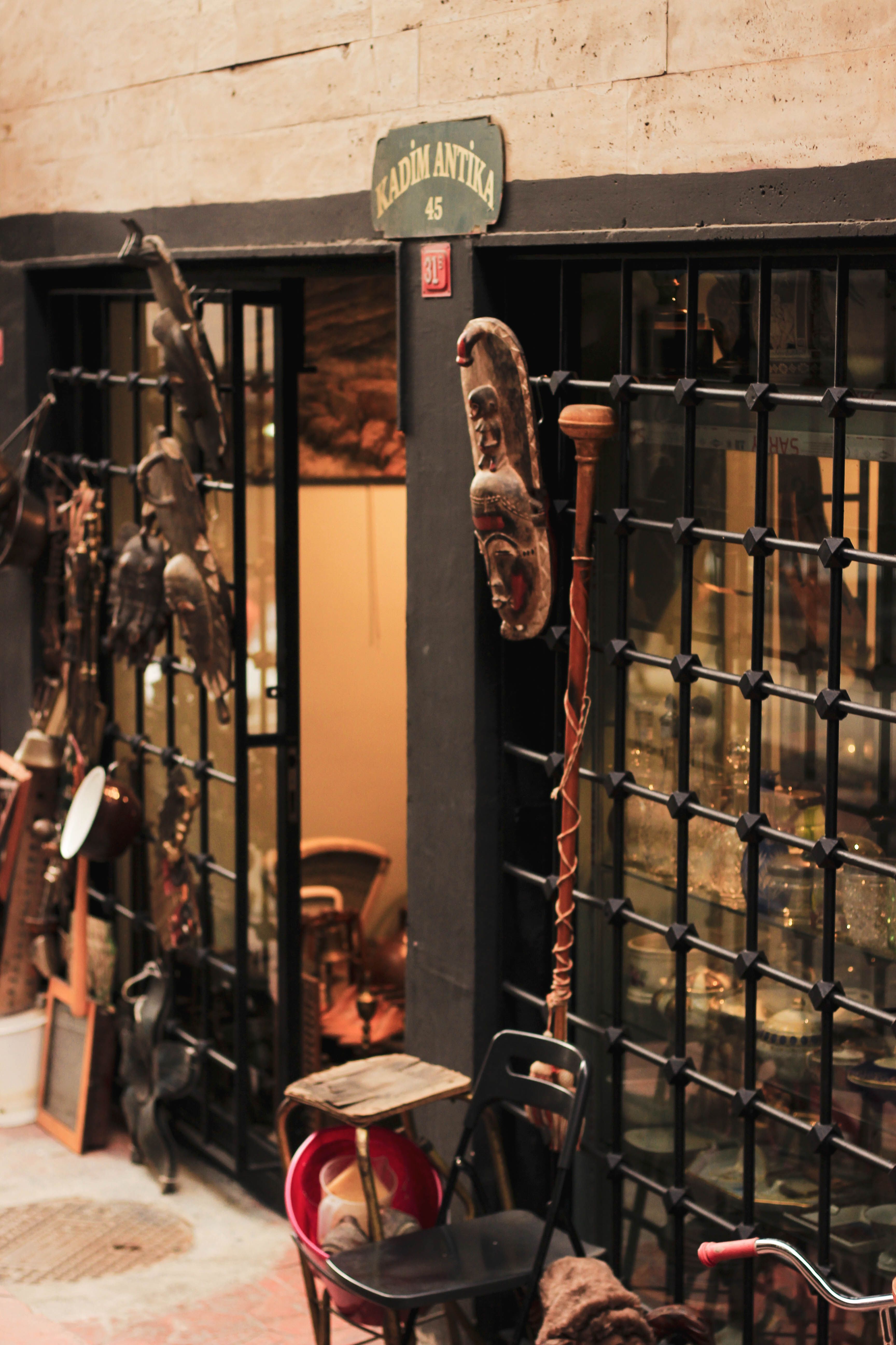 Antique shop entrance adorned with African masks and sculptures in urban setting.