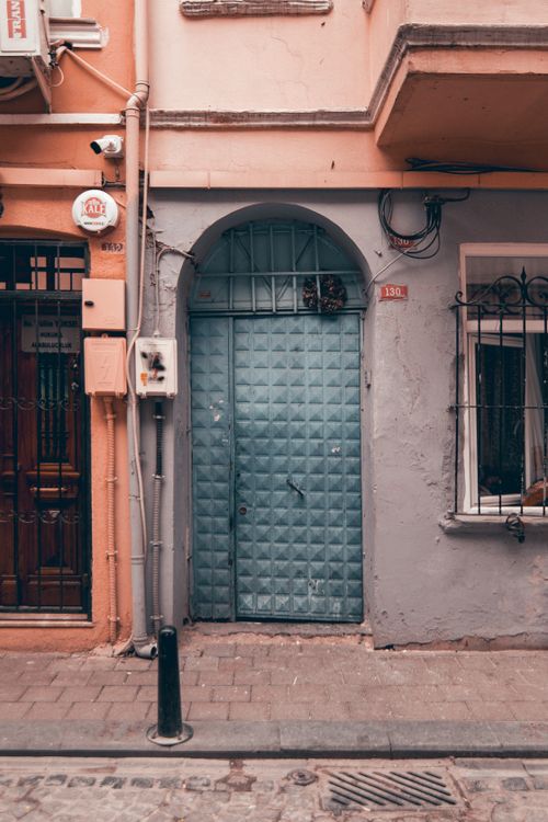 Free Colorful urban facade featuring an ornate blue door framed by pastel walls and intricate metalwork windows. Stock Photo