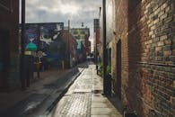 探索一条狭窄的城市小巷，在自然阳光下捕捉到充满活力的涂鸦和潮湿的人行道