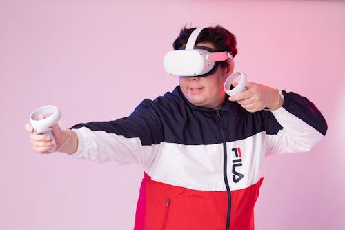 Man in a Jacket Wearing a VR Headset and Holding the Controllers