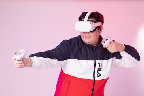 Man in a Jacket Wearing a VR Headset and Holding the Controllers