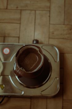 A brown coffee pot on an electric stove viewed from above, creating a warm kitchen vibe.