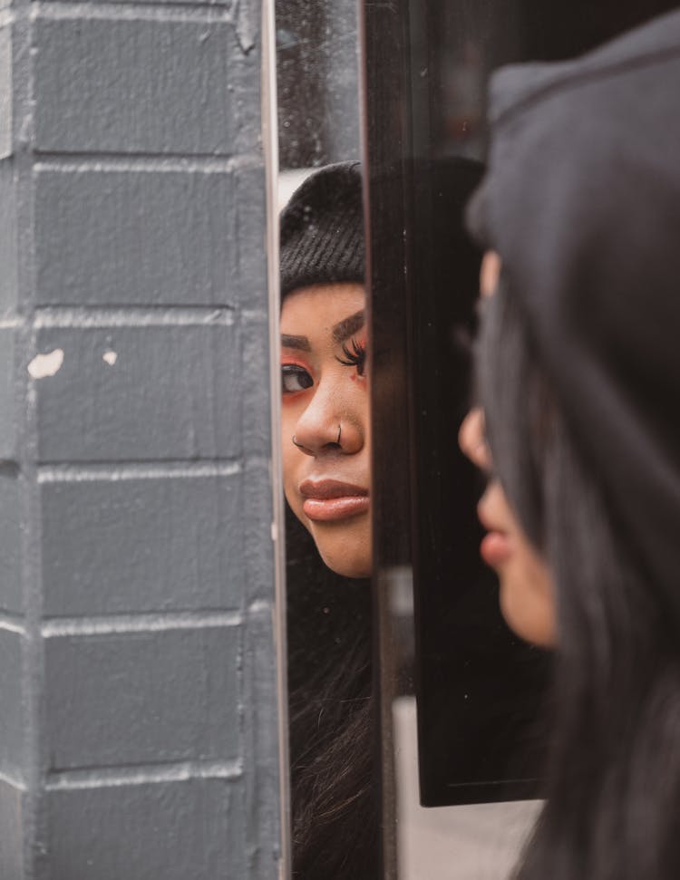 Reflection Of Woman With Black Hood In Mirror On Wall