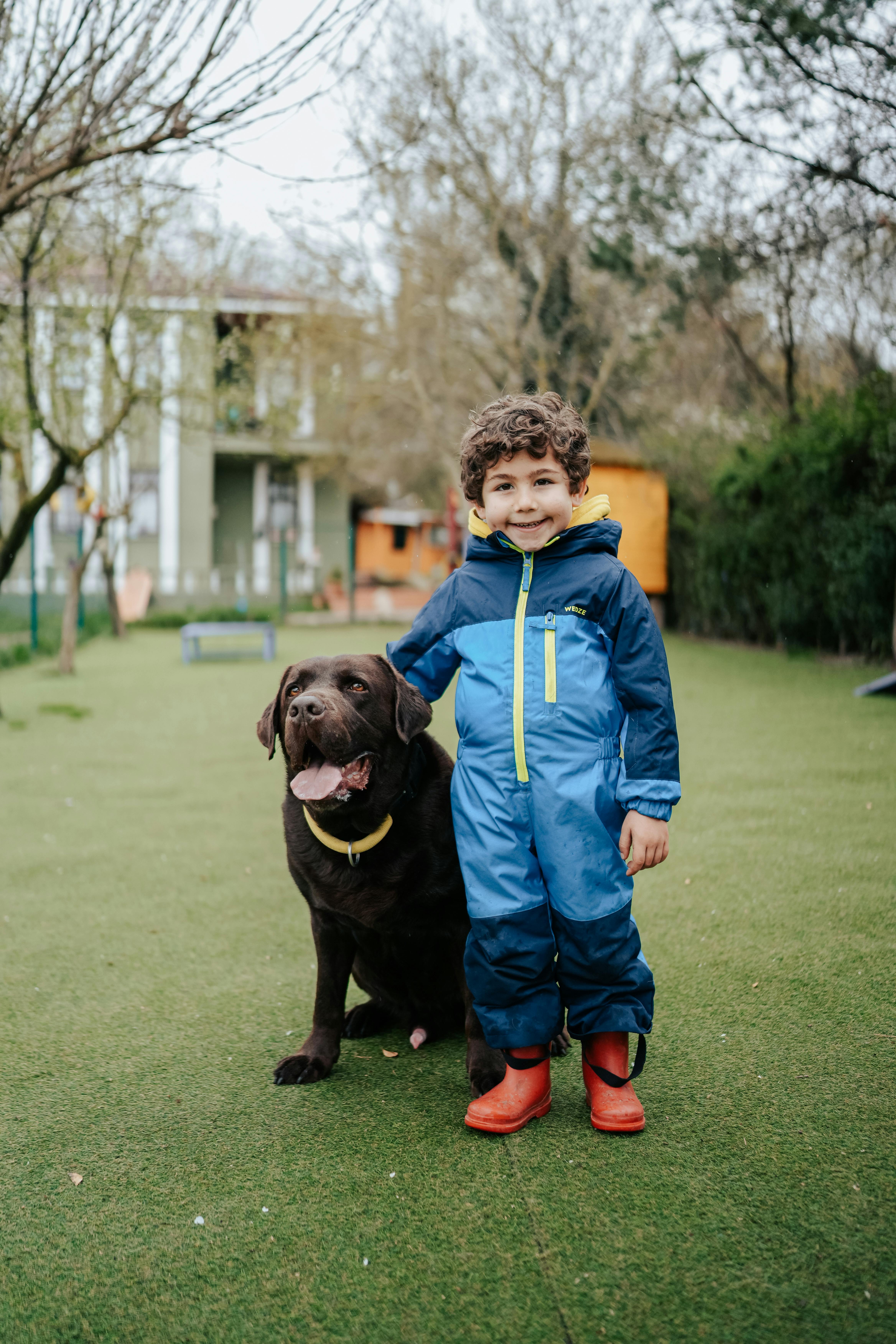 smiling boy with dog posing in garden