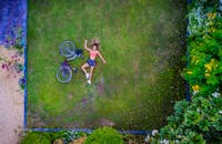 航拍照片中，一名妇女躺在迪拜花园的草坪上，旁边停着一辆自行车