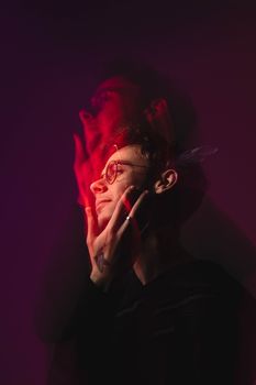 A creative studio portrait of a man with glasses and motion blur, set against a red background.
