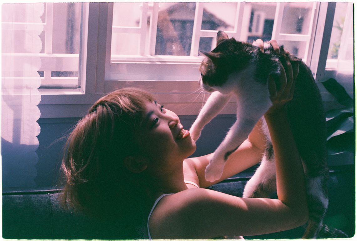 Woman lifting her cat affectionately in natural window light
