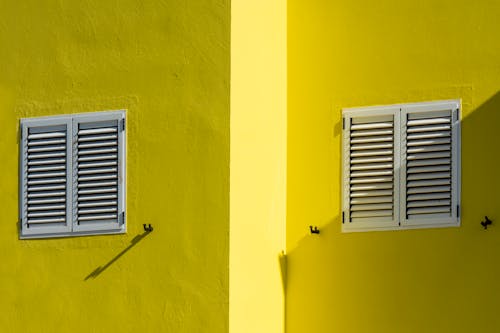 Close-up of a Yellow Building with White Window Shutters 