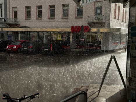 Rain falls on a city street in Bad Säckingen, Germany, showing urban life and weather.