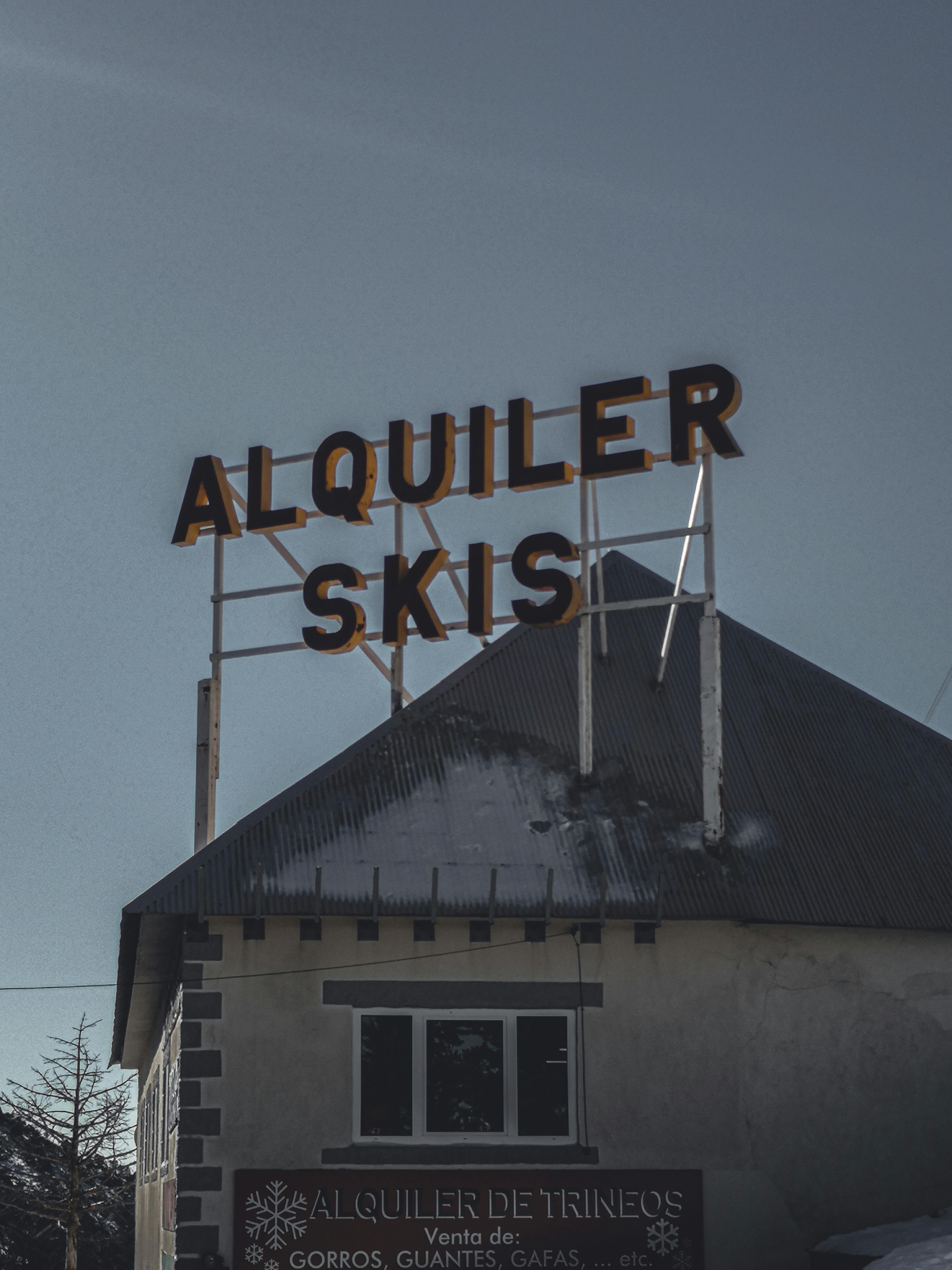 Prescription Goggle Inserts - A rooftop sign for 'Alquiler Skis' on a building in Spain, with clear blue sky.