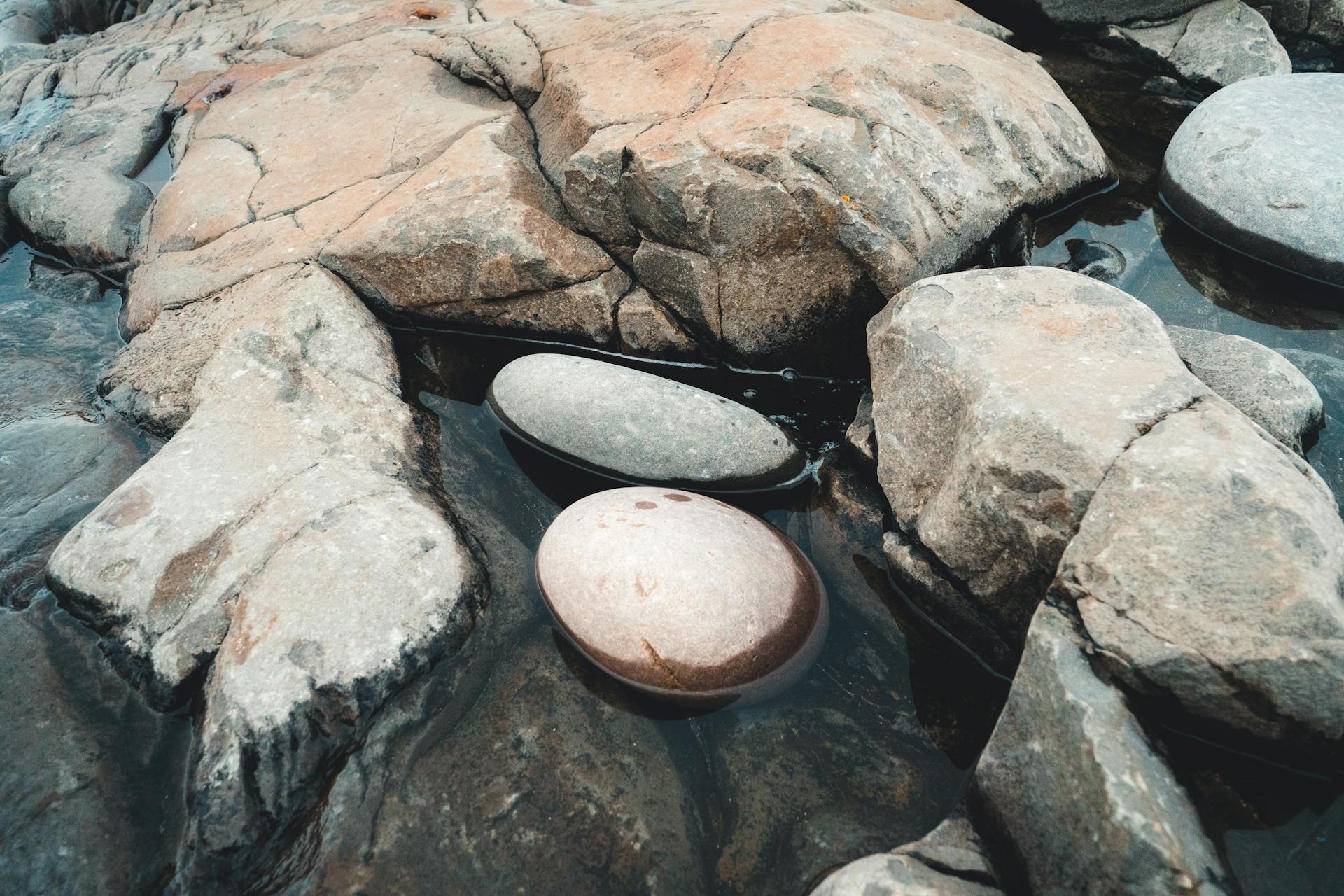 Close-up of smooth round stones submerged in water, showcasing natural rock formations.