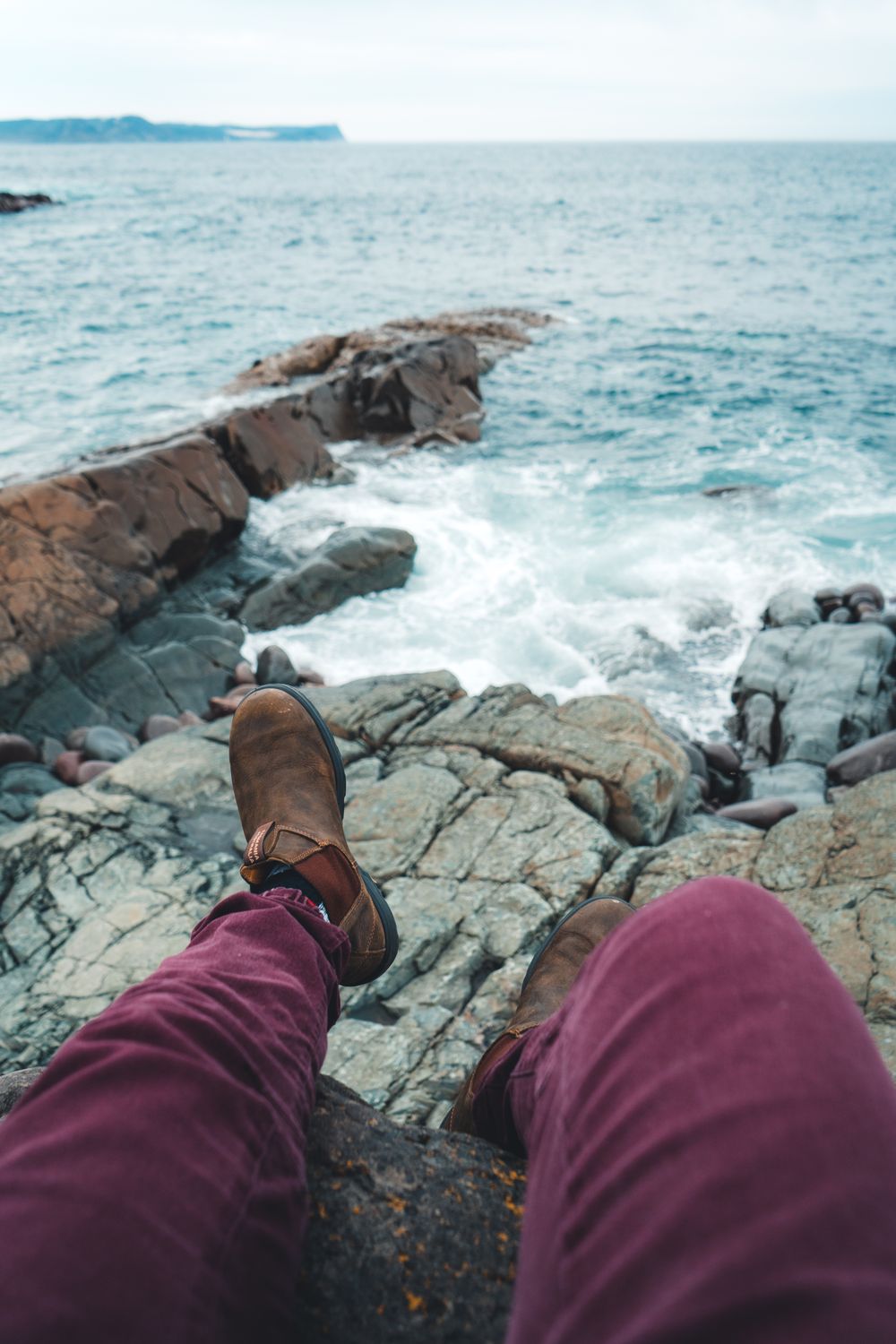 Person Sitting on Rocks by the Sea · Free Stock Photo