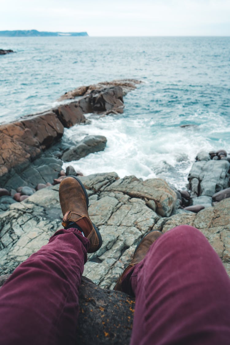 Person Sitting On Rocks By The Sea