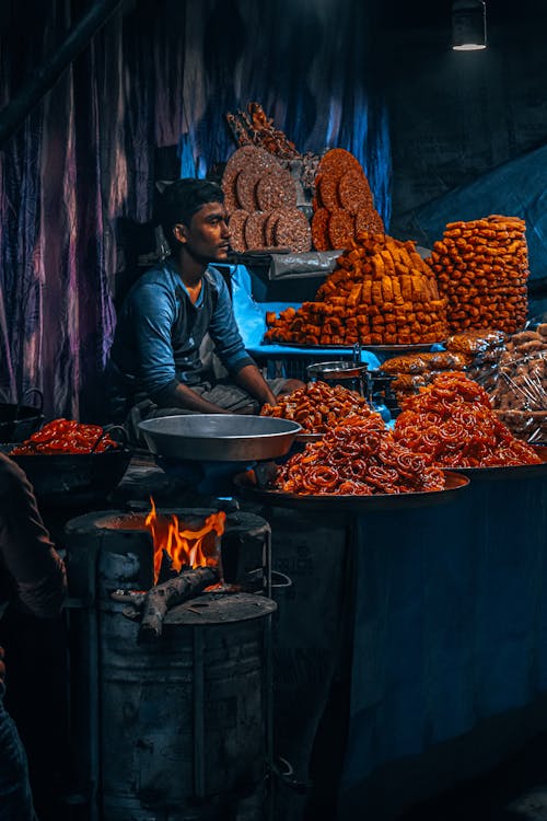 A Man Sitting behind the Counter at a Food Market Stall 