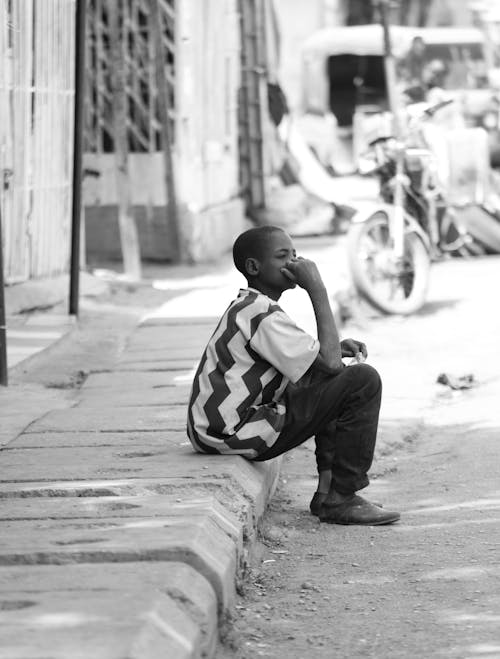 Free Young Boy Sitting on Curbside Stock Photo