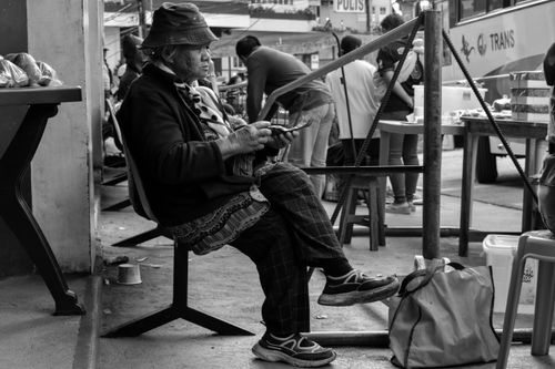 Free A black and white image of an elderly woman sitting and waiting on the street. Stock Photo