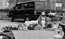 一名菲律宾街头小贩在停放的车辆旁出售水果和蔬菜