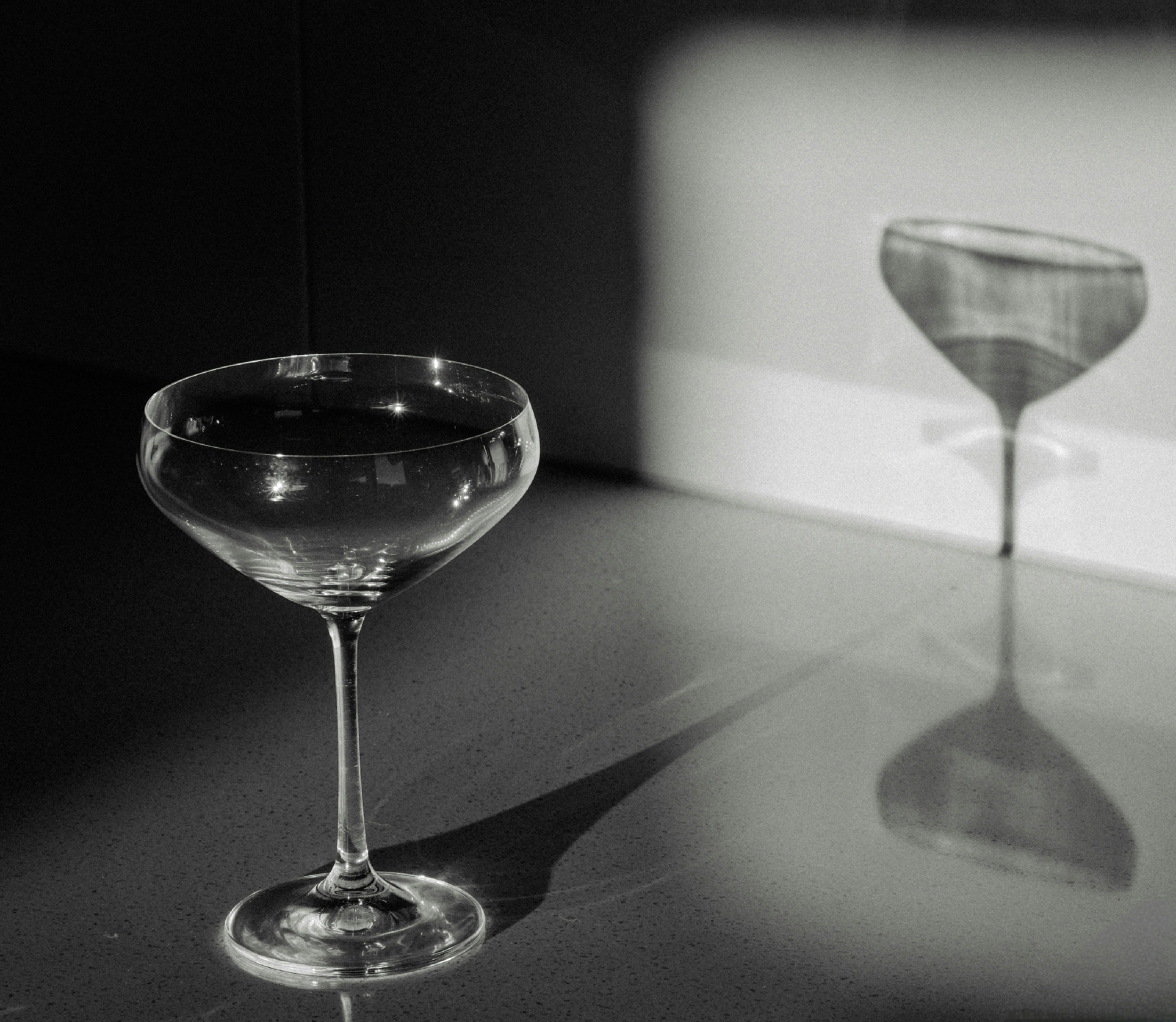 https://images.pexels.com/photos/16196149/pexels-photo-16196149/free-photo-of-black-and-white-photo-of-martini-glass-casting-shadow-on-wall.jpeg