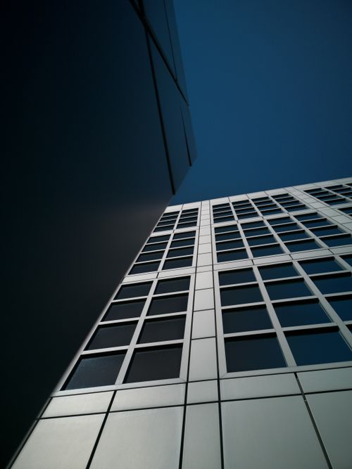 Free Low angle view of a sleek, modern skyscraper against a clear blue sky. Stock Photo