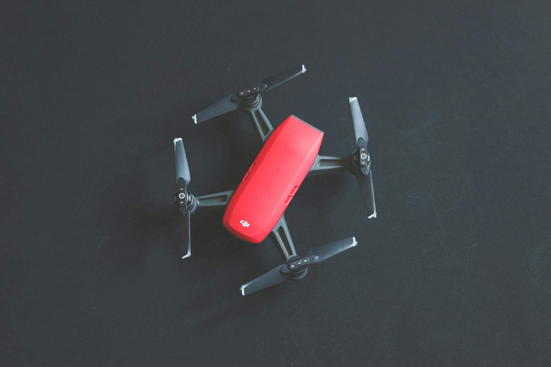 A vibrant red DJI drone captured from above on a black background, showcasing modern technology.