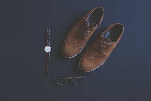 免费 眼镜和手表旁边的棕色皮革方鞋 素材图片
