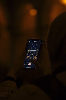 A person recording with a smartphone in a dimly lit environment, capturing details on screen.