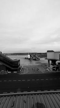 A monochrome scene capturing an airplane on the tarmac at Madrid Airport.