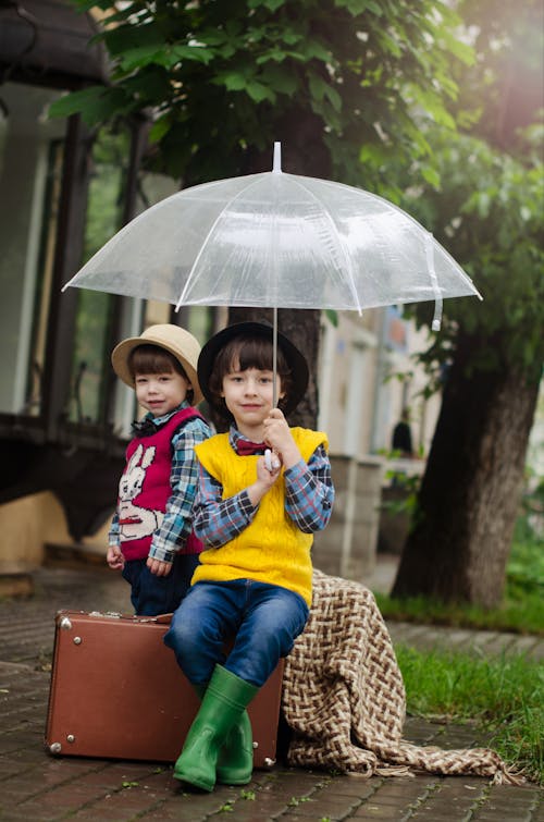 Girl Holding Umbrella En étant Assis Sur Une Valise Marron