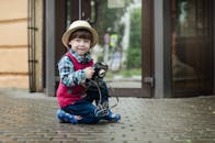 一个可爱的幼儿男孩坐在户外，拿着老式相机，脸上露出好奇和喜悦的神情