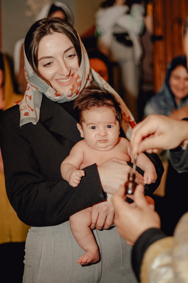 Smiling Woman Holding Baby On Christening In Church