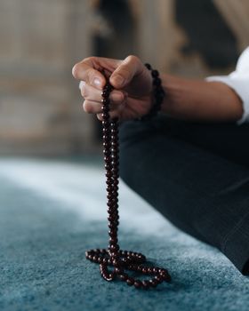 A person holds Islamic prayer beads in quiet reflection, showcasing faith and spirituality.