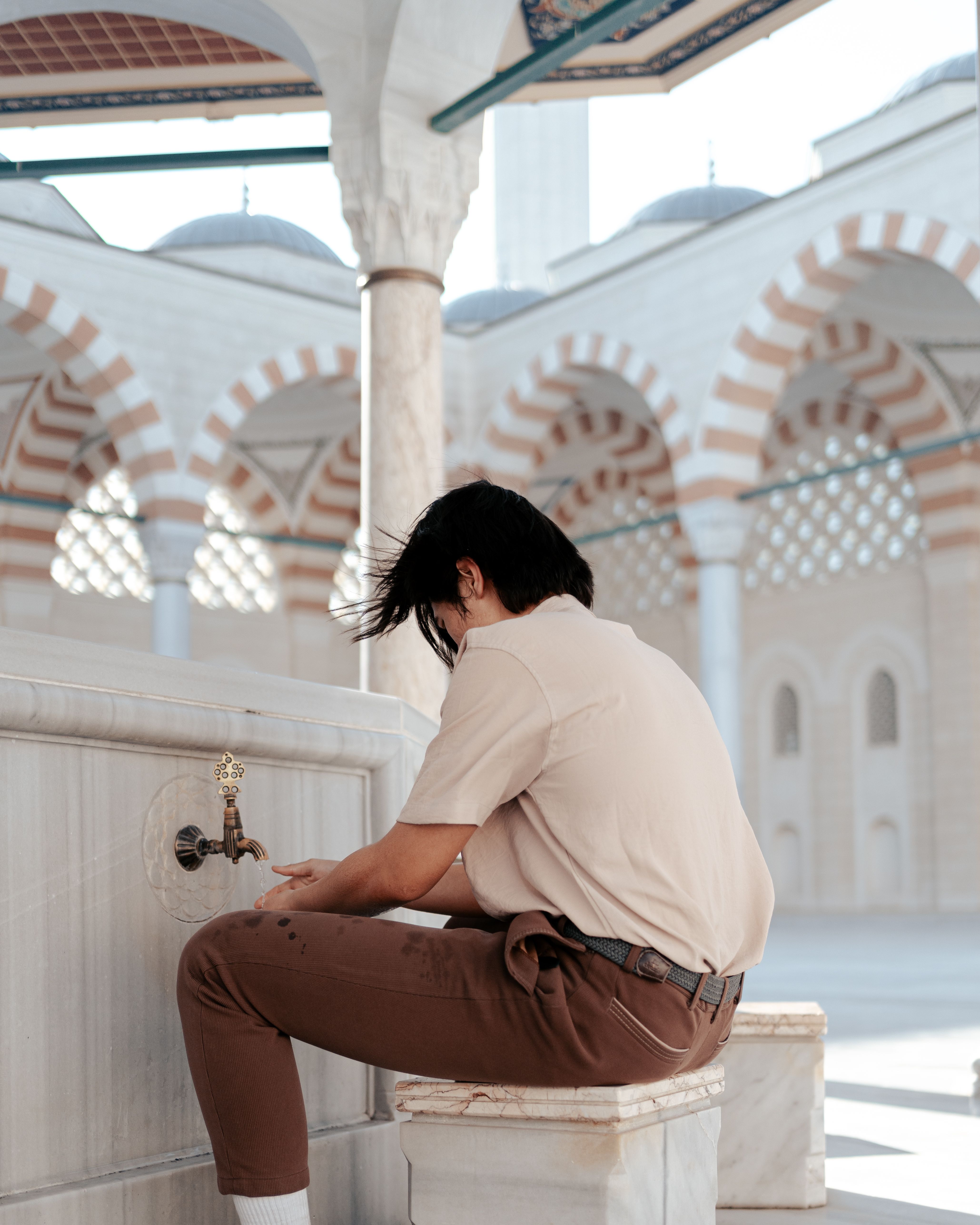 Young Man Performing Wudu in Mosque Courtyard · Free Stock Photo