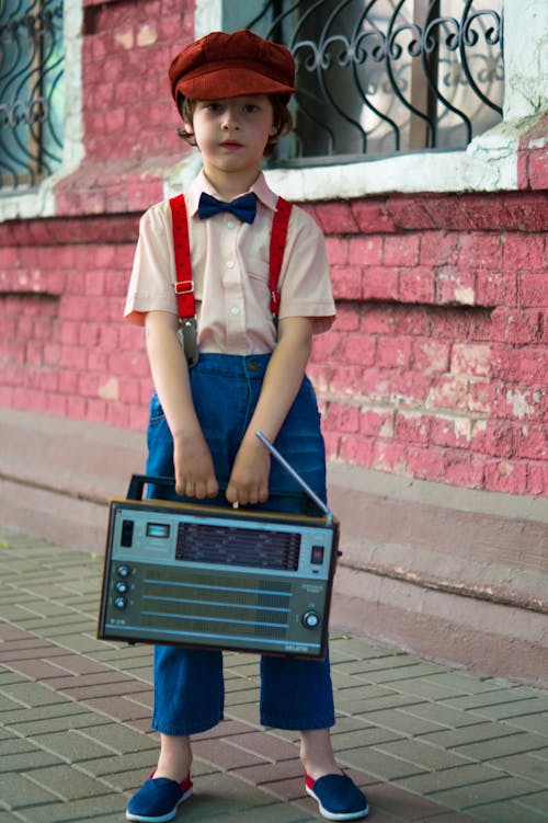 Zdjęcie Chłopca Trzymającego Radio I Stojącego Obok Czerwonego Domu
