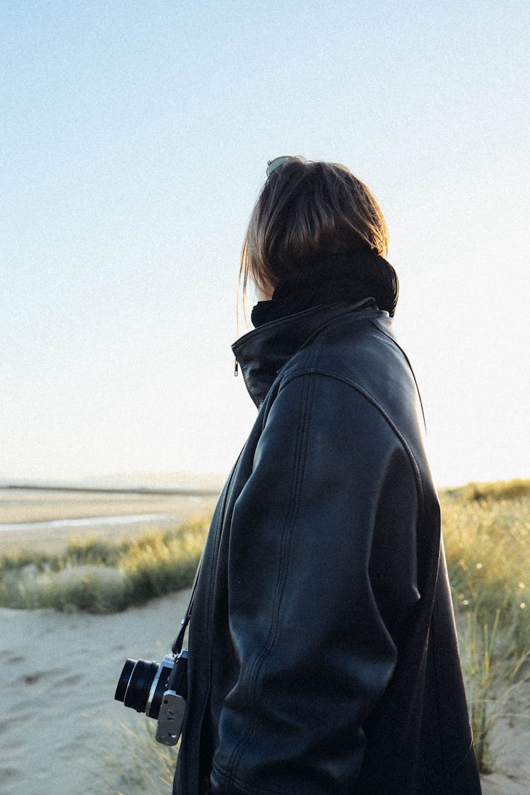 Woman In A Leather Jacket And With A Camera On The Beach 