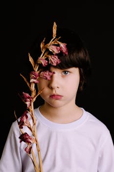 一幅以黑暗为背景、手持干花的儿童艺术肖像