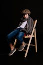 一个穿着时髦的小男孩在黑暗背景下的木椅上摆姿势