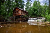 一座历史悠久的木磨坊坐落在宁静的瀑布旁，四周环绕着郁郁葱葱的森林