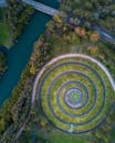 一条流动的河旁边，郁郁葱葱的绿色公园里，圆形花园的设计呈现出令人惊叹的鸟瞰图