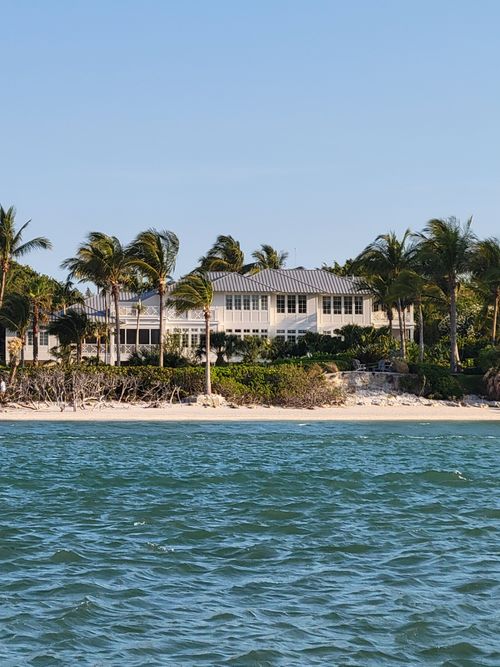 Free Elegant beachfront property with palm trees, ocean view, and clear sky. Stock Photo