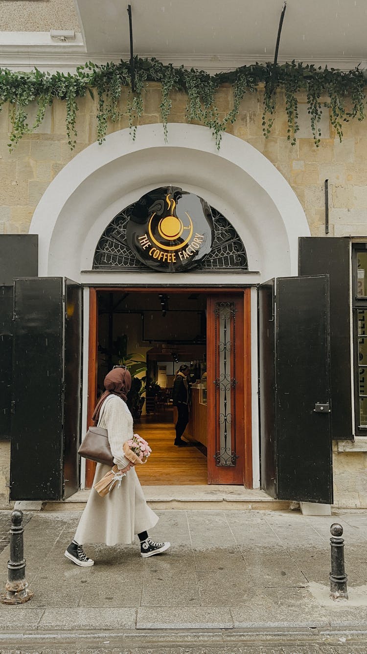 Woman Walking Near Cafe Entrance