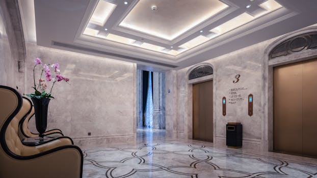 Opulent hotel lobby interior featuring marble floors and an elevator area with floral decoration.