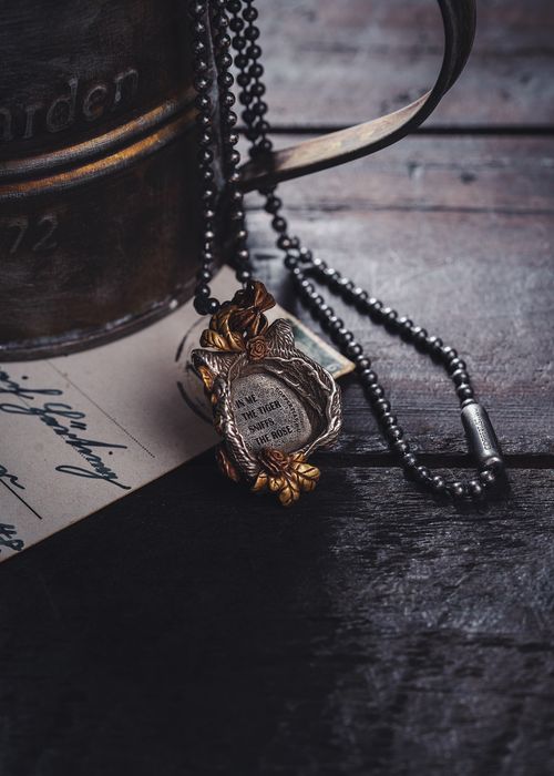 Free Close-up of a vintage pendant necklace resting on a rustic wooden surface with handwritten background. Stock Photo