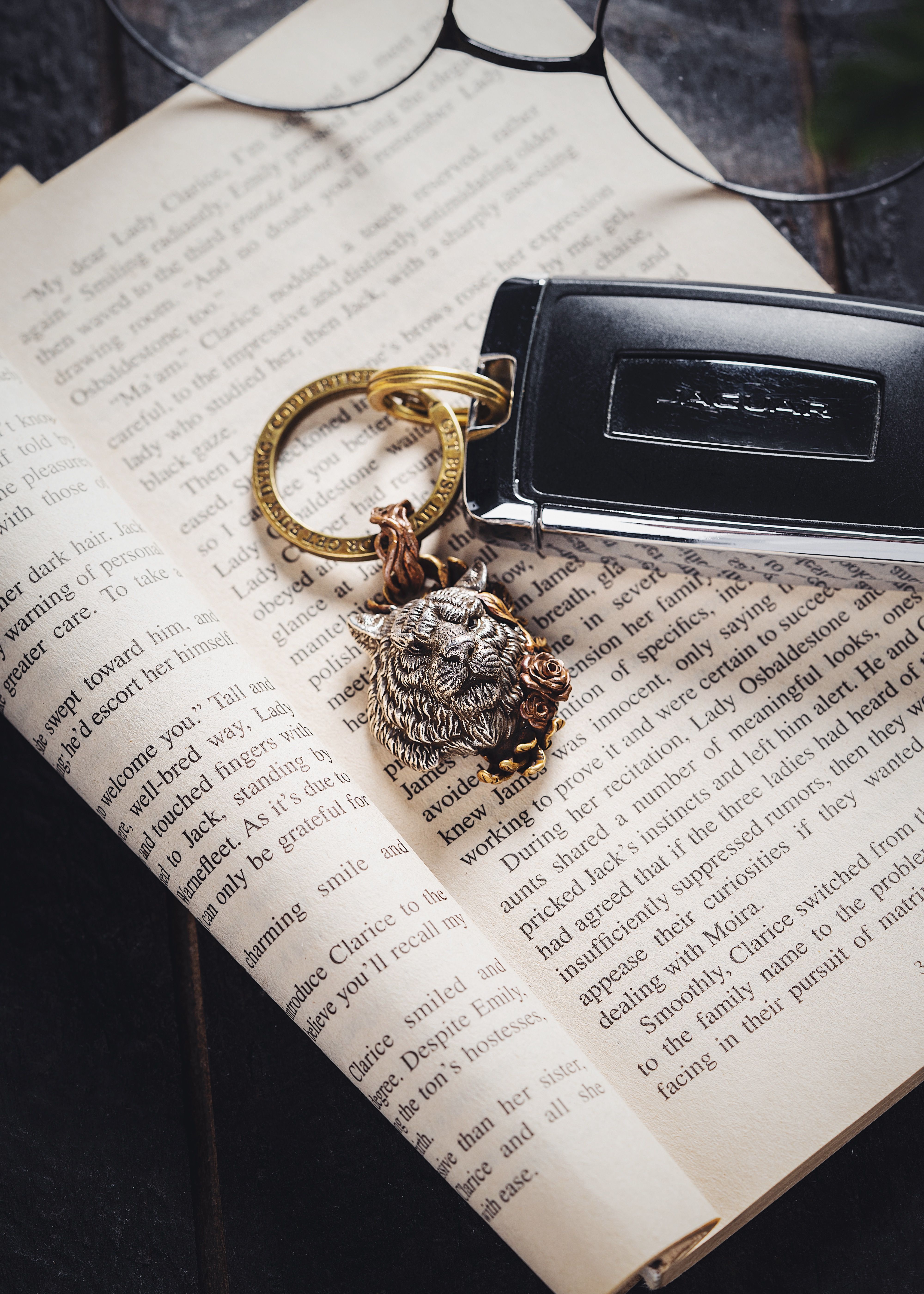 Stylish lion brooch keychain on an open book page, symbolizing elegance and literature.