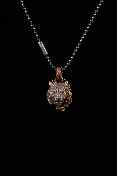Free Detailed tiger pendant with floral design on a silver bead chain. Stock Photo
