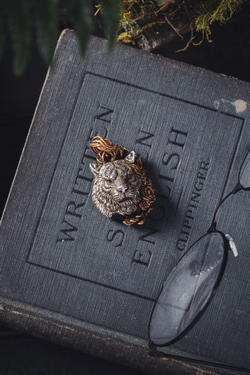 Free Close-up of a vintage brooch shaped like a tiger on an old English language book with glasses. Stock Photo