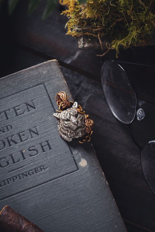 Free A vintage book adorned with a tiger brooch and reading glasses on a rustic table. Stock Photo